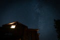 Lonely glowing window in a wooden house, silhouette against the starry sky Royalty Free Stock Photo