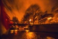 Night lighting reflections in Amsterdam channels from moving cruise boat. Blurred abstract photo as background.