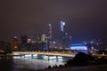 Night modern city with skyscrapers. Bridge over the river, city buildings glow at night. The sky in the clouds hides the building.