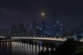 Night modern city with skyscrapers. Bridge over the river, city buildings glow at night. The sky in the clouds hides the building.