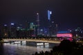 Night modern city with skyscrapers. Bridge over the river, city buildings glow at night. The sky in the clouds hides the building.