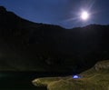 Night mountain landscape with illuminated blue tent. Mountain peaks and the moon. outdoor at Lacul Balea Lake, Transfagarasan, Royalty Free Stock Photo