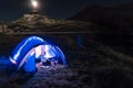 Night mountain landscape with illuminated blue tent. Mountain peaks and the moon. outdoor at Lacul Balea Lake, Transfagarasan, Royalty Free Stock Photo