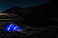 Night mountain landscape with illuminated blue tent. Mountain peaks and the moon. outdoor at Lacul Balea Lake, Transfagarasan, Royalty Free Stock Photo