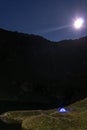 Night mountain landscape with illuminated blue tent. Mountain peaks and the moon. outdoor at Lacul Balea Lake, Transfagarasan, Royalty Free Stock Photo