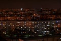 Night panorama of the city overlooking residential buildings with many glowing windows.