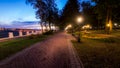 A night park lit by lanterns with a stone pavement, trees, fallen leaves and benches in early autumn Royalty Free Stock Photo