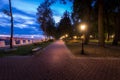 A night park lit by lanterns with a stone pavement, trees, fallen leaves and benches in early autumn Royalty Free Stock Photo