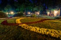 A night park lit by lanterns with a stone pavement, trees, fallen leaves and benches in early autumn Royalty Free Stock Photo