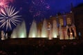 Night photo of the festive salute above the building of the opera and ballet theater and fountains with backlight.