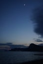 Night photo of sea landscape with mountains and moon in the sky. Royalty Free Stock Photo