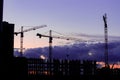 Night photography of a construction site, silhouettes of a lift-up in red and an unfinished residential building, gloomy blue sky Royalty Free Stock Photo