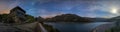 Night photography of a landscape of the Alps. Lake with stars in the sky and moving clouds and the moon