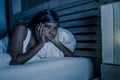 Night portrait of young sad and worried black african American woman in bed at home sleepless and stressed feeling depressed suffe