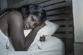 Night portrait of young sad and worried black afro American woman in bed at home sleepless and stressed feeling depressed sufferin Royalty Free Stock Photo