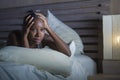 Night portrait of young scared and stressed black african American woman on bed upset unable to sleep suffering hangover headache Royalty Free Stock Photo