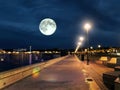 Fool moon at night sky sea  promenade night promenade at sea people walk and relax town harbor street light blurred at sea water f Royalty Free Stock Photo