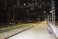 Night railway station. Snowfall. The lights of the city in the background.