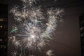 Night salute. Explosion lines of different colors. Outbreaks between houses Royalty Free Stock Photo