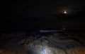 Night scene on the beach. Illuminated in the foreground. And a lunar path in the sea reflected from the moon. Top view. Royalty Free Stock Photo