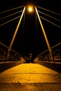 Symmetrical night scene of a cable-stayed bridge with cables forming guide lines to a girl with her back turned walking. Royalty Free Stock Photo