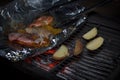 Night scene of cooking potato and seafood in foil on grill Royalty Free Stock Photo