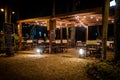 Night scene of an elegant outdoor bar illuminated by small hanging bulbs