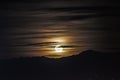 Night scene - full moon shining brightly in sky with clouds on mountains background. Royalty Free Stock Photo