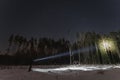 Night scene, a man with a flashlight in the forest in winter. Starry sky