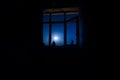 Night scene of moon seen through the window from dark room. Royalty Free Stock Photo