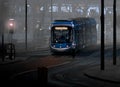 A night scene of a tram on a foggy night at a city center tram stop and illuminated office building Royalty Free Stock Photo