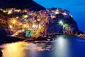 Night scenery of Manarola, an amazing village on vertical cliffs by the rocky coast in Cinque Terre National Park, with lights