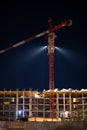 Night shooting, construction of an apartment building, erection of the floors of a multi-storey building. Construction crane