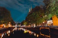 Night shot of Amsterdam canal with illuminated steeples of the church De Krijtberg in downtown Netherlands Royalty Free Stock Photo