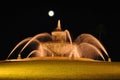 Night shot of fountain with blurred water and full moon and stars
