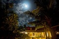 Night shot with palm trees and moon with clouds over a restaurant on the beach. Magical in background, tropical  night Royalty Free Stock Photo