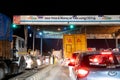 Night shot of vehicles waiting at NHAI toll booth while a large white headboard talks about FASTag and Paytm