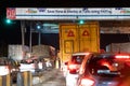 Night shot of vehicles waiting at NHAI toll booth while a large white headboard talks about FASTag and Paytm