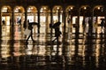 Night silhouette of people with umbrella on a rainy night in Saint Mark`s Square in Venice with golden light in backgr Royalty Free Stock Photo