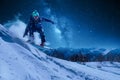 Night skating snowboarder is jumping with snowboard under the starry sky and moonlight