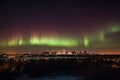 a night sky, with aurora dancing above a city skyline