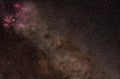 Night sky, many stars with milky way around Cygnus constellation, Red purple nebulosity around Sadr star visible. Long exposure