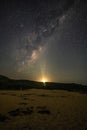 Night sky, milky way and rising moon sliver with lightburst