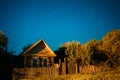 Night sky over old house in village. Night starry sky above house with bright stars and meteoric track trail. Glowing