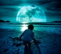 Night sky with super moon. Girl digging in sand. Concept of conn Royalty Free Stock Photo