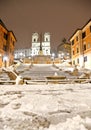 Night snowfall on empty Spanish square and steps in Rome with church Trinita di Monti in background, Italy. Piazza di Spagna