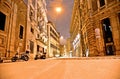 Night snowfall in empty street in the historic center of Rome with cars and road surface completely covered by snow