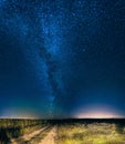 Night starry sky above country road in countryside and green field Royalty Free Stock Photo