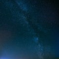 Night Starry Sky Above Field And Yellow City Lights On Backgroun