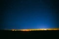 Night Starry Sky Above Field And Yellow City Lights On Background Royalty Free Stock Photo